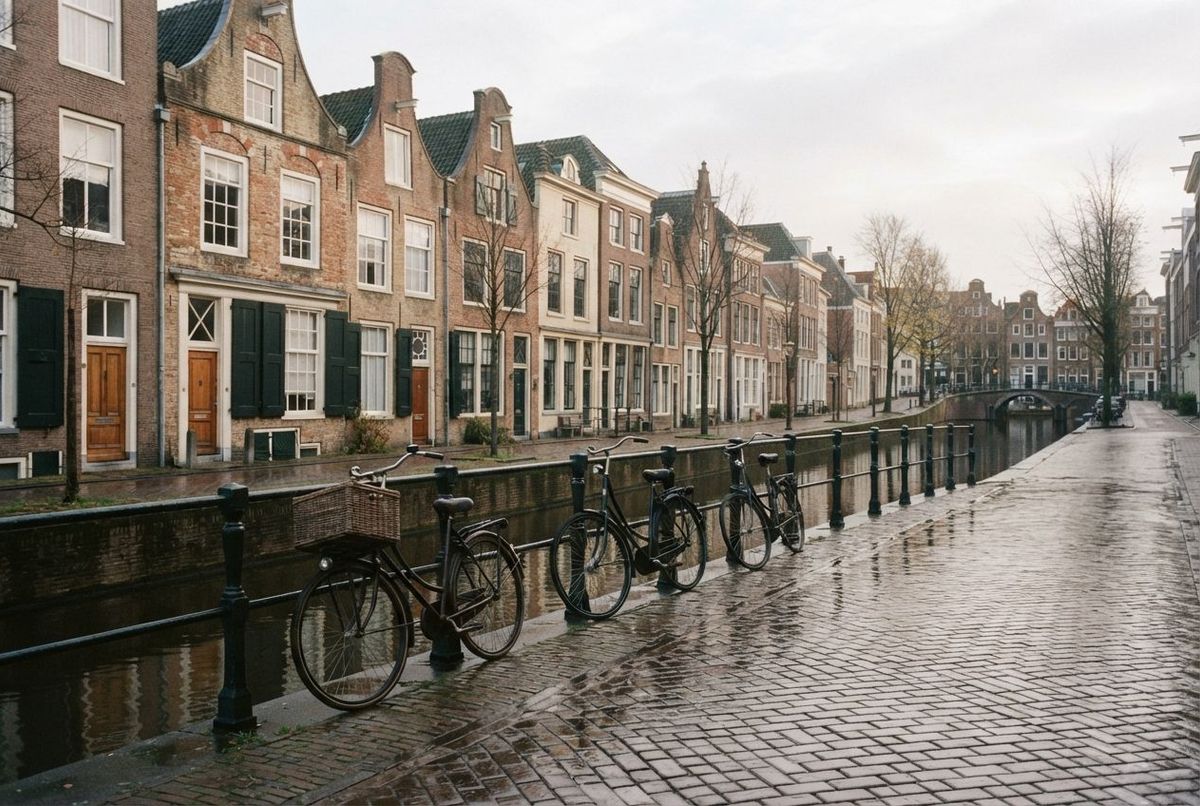 A quiet canal street in a Dutch city on a grey morning, bicycles along the railing.